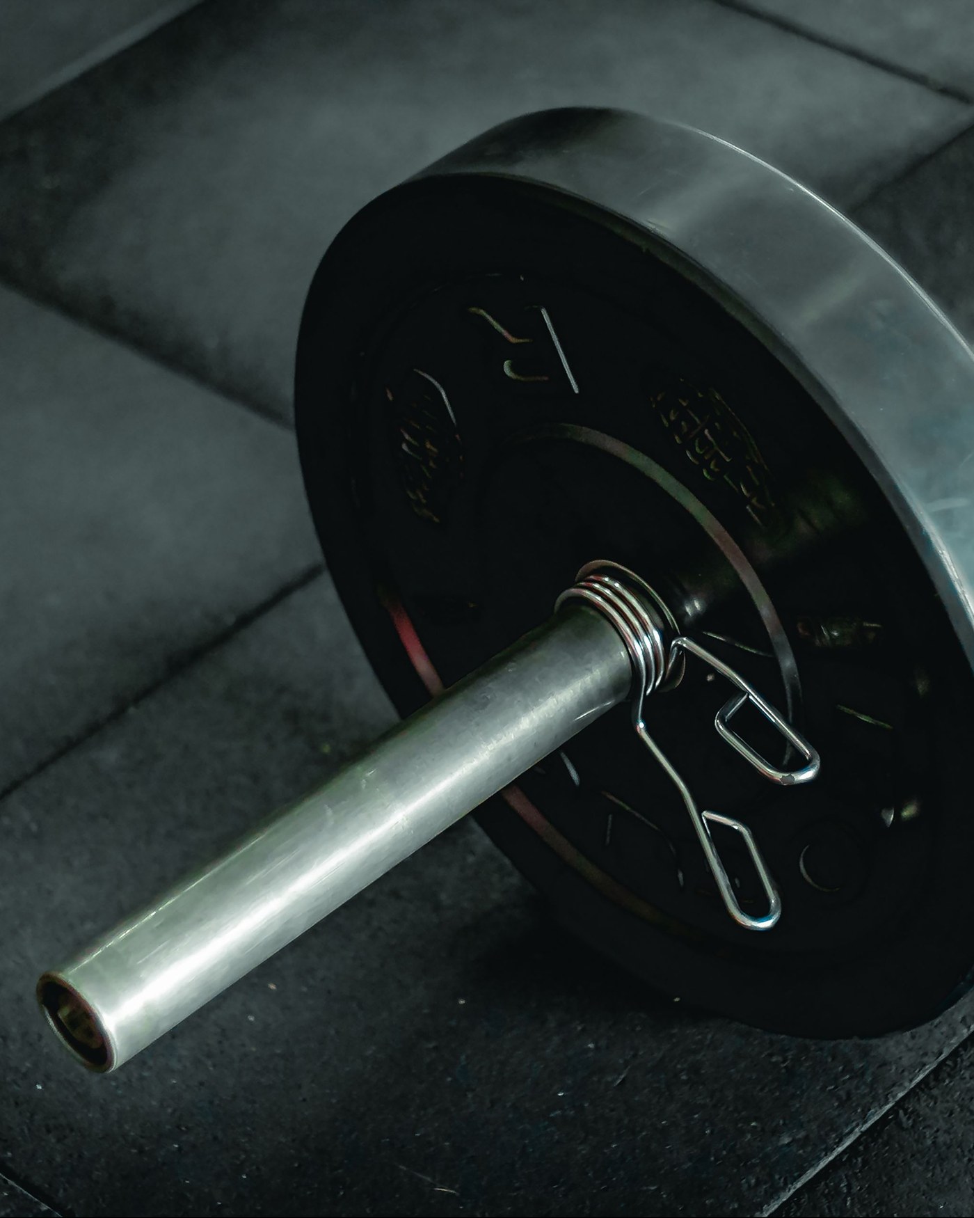 Disco y barra apoyados en el piso de goma del gimnasio